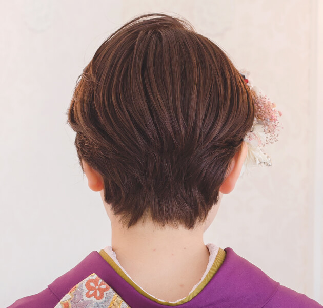 薄ピンクと白い花飾りを付けたショートヘアのモデルの後ろ姿写真