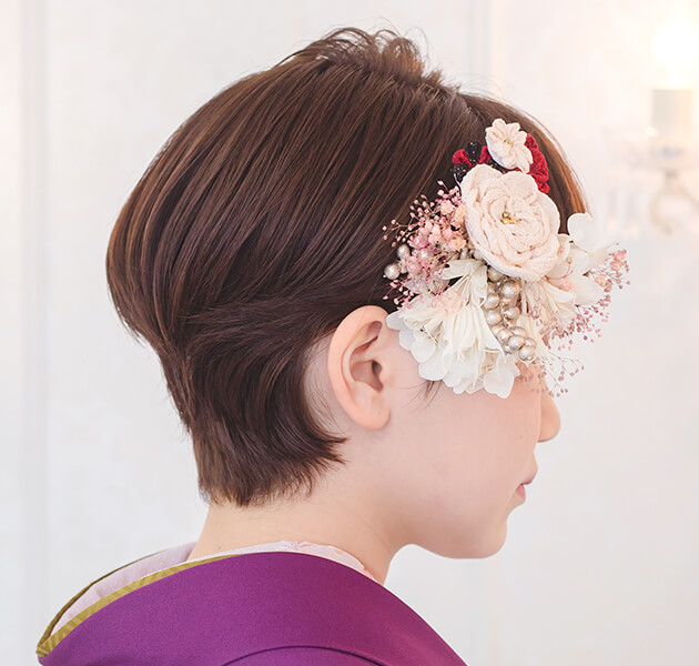 薄ピンクと白い花飾りを付けたショートヘアのモデルの横顔写真