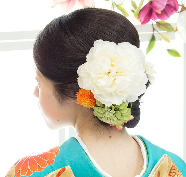 白の花飾りをあしらい大人っぽいシニヨンのモデルの左横顔姿写真