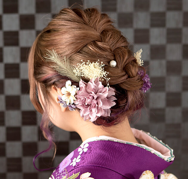 薄紫の花飾りと編み込まれたシニヨンのモデルの後ろ姿写真
