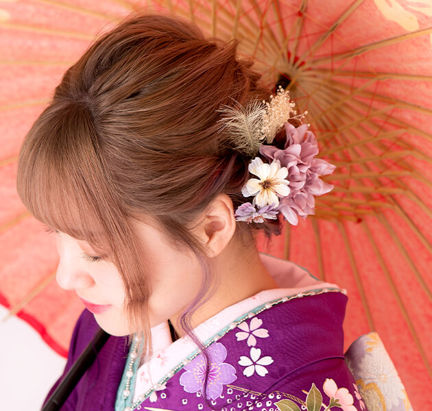 薄紫の花飾りと編み込まれたシニヨンのモデルの横顔写真