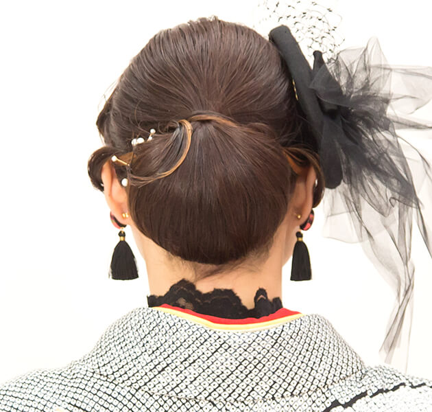 黒のレース素材の髪飾りと前髪を波打たせたシニヨンのモデルの後ろ姿写真