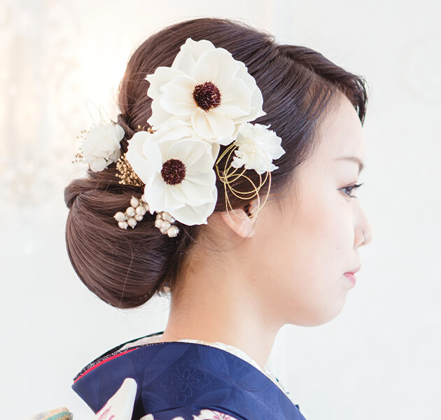 白い花飾りとシンプルなシニヨンのモデルの右横顔写真